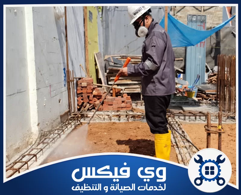 شركة رش دفان بحفر الباطن 0544909308 شركة وي فيكس عامل في موقع بناء يرتدي معدات الحماية ويرش المياه لتنظيف الأرض ومعالجة الموقع بدقة احترافية